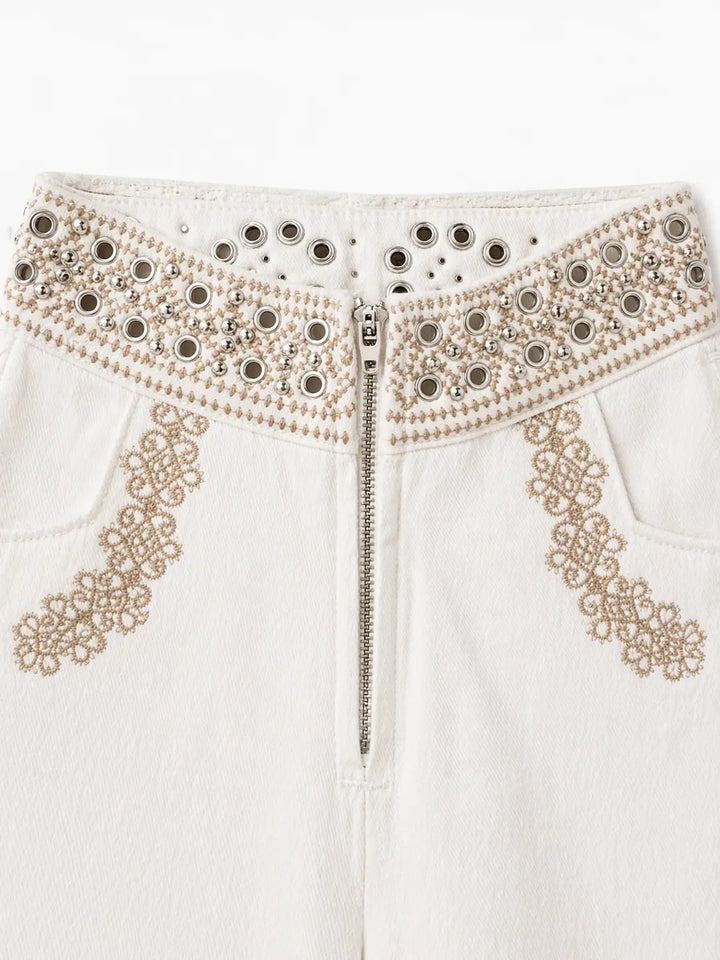 Pantalón recto crudo con bordados geométricos y ojales.