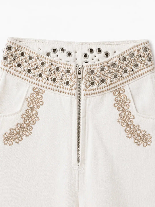 Pantalón recto crudo con bordados geométricos y ojales.